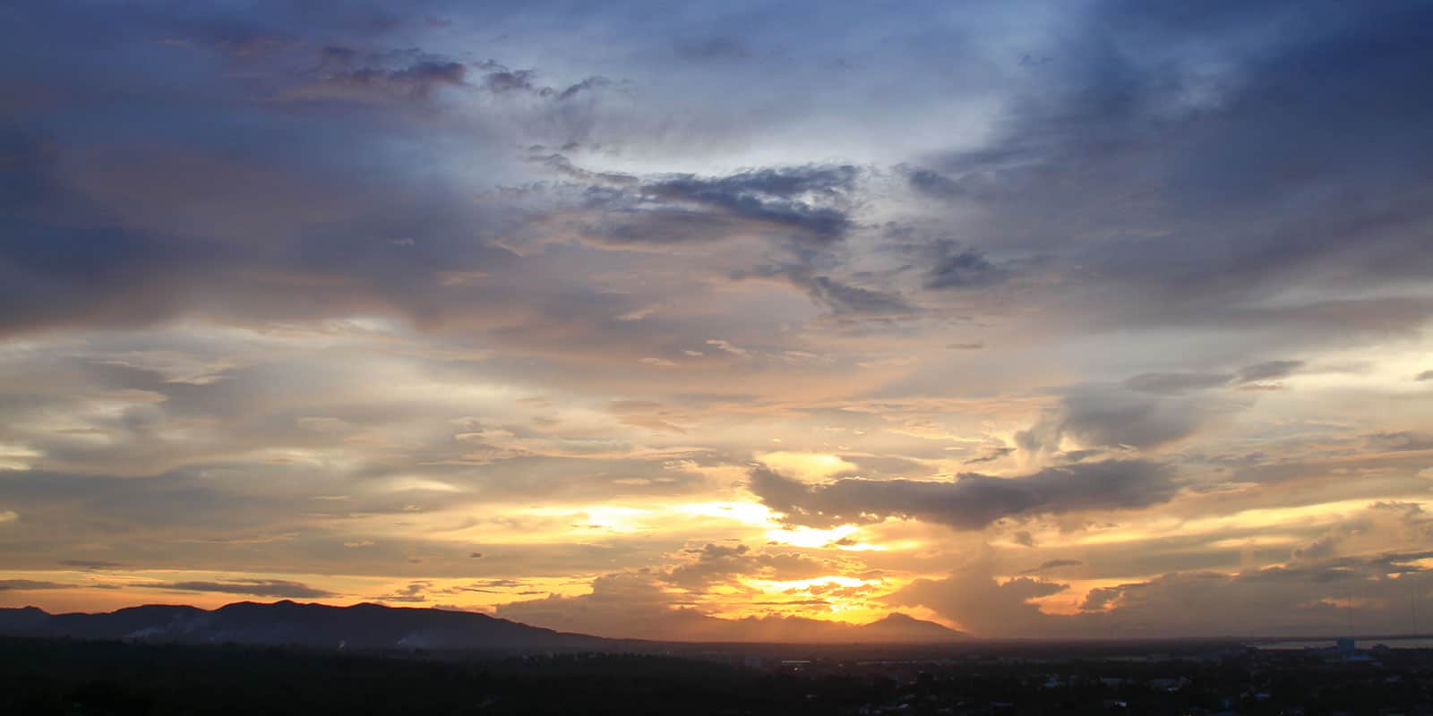 A beautiful panoramic shot of a violet and orange sun set/rise with mountains in the background.