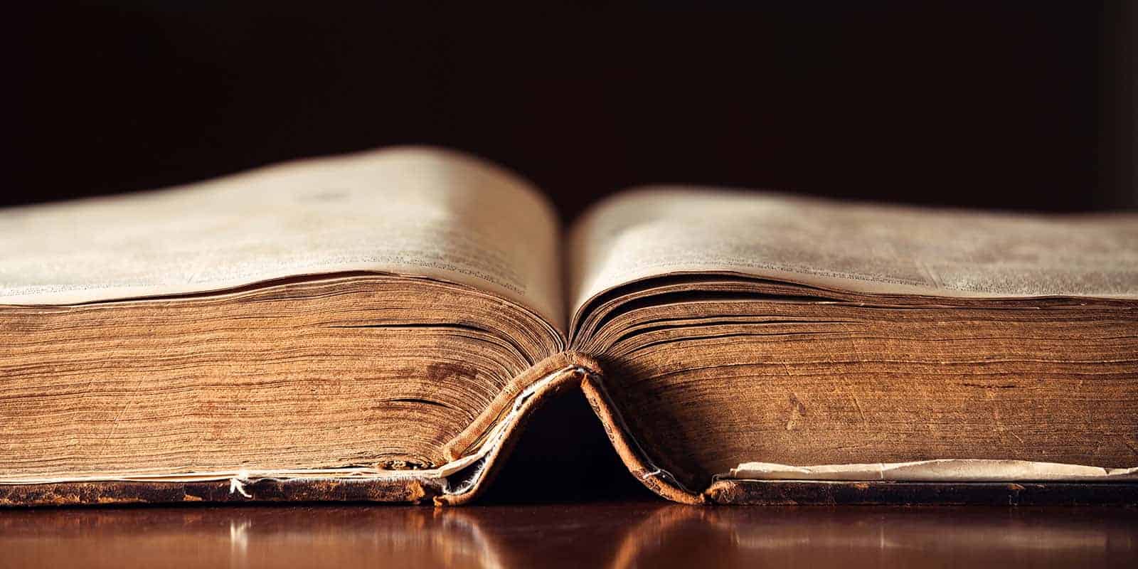 A close-up of an old Bible splayed out on a table.