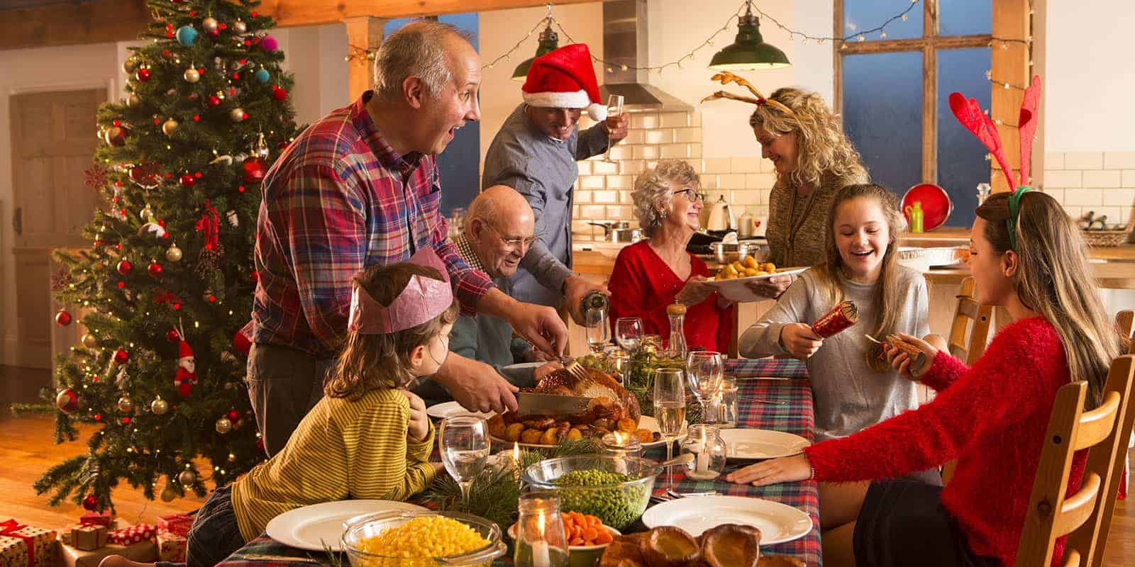 A very happy family gathered around a table at Christmas cutting the Christmas turkey.