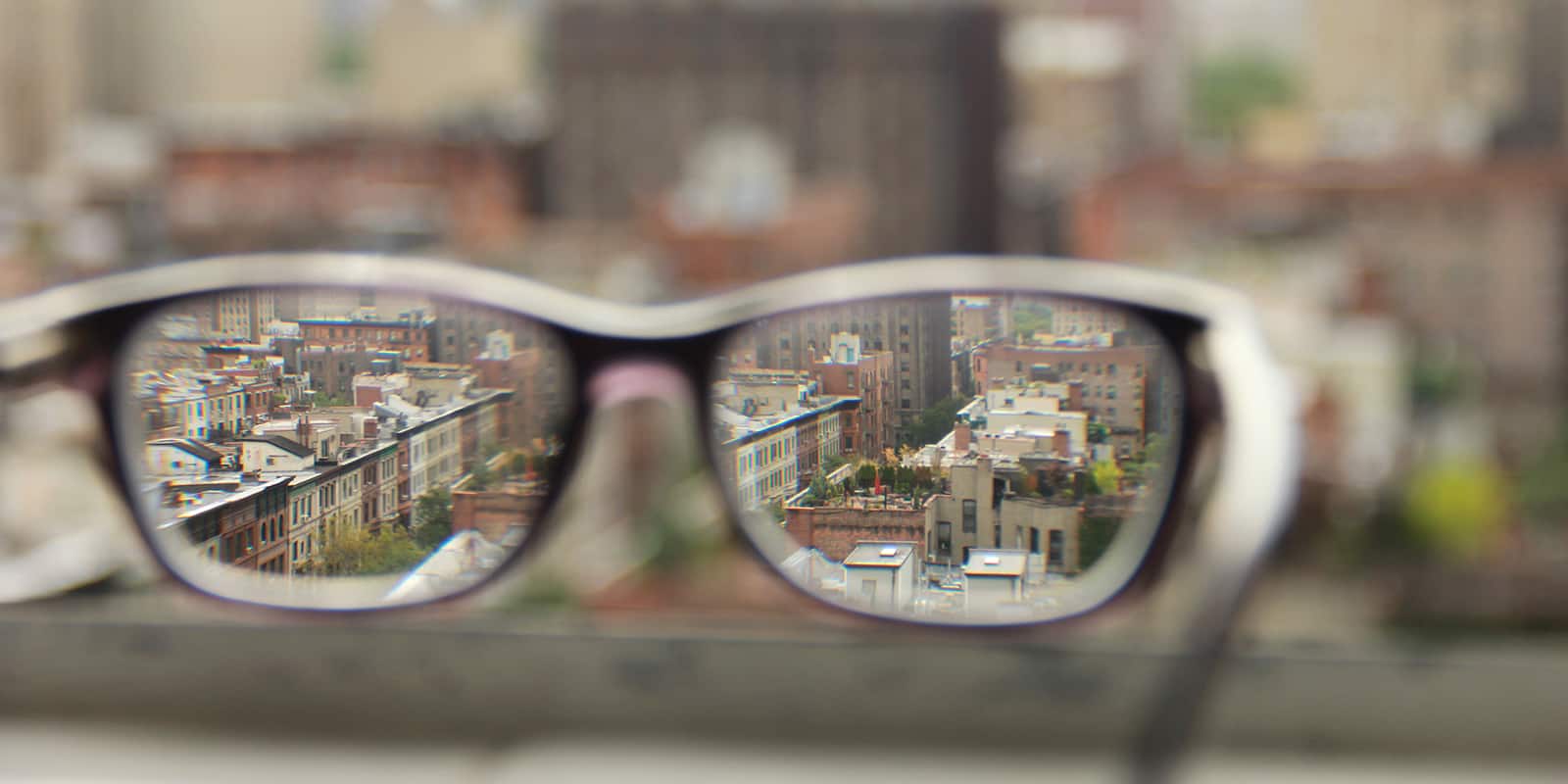 a pair of glasses looking out over a city, with the lenses in focus and the background blurred